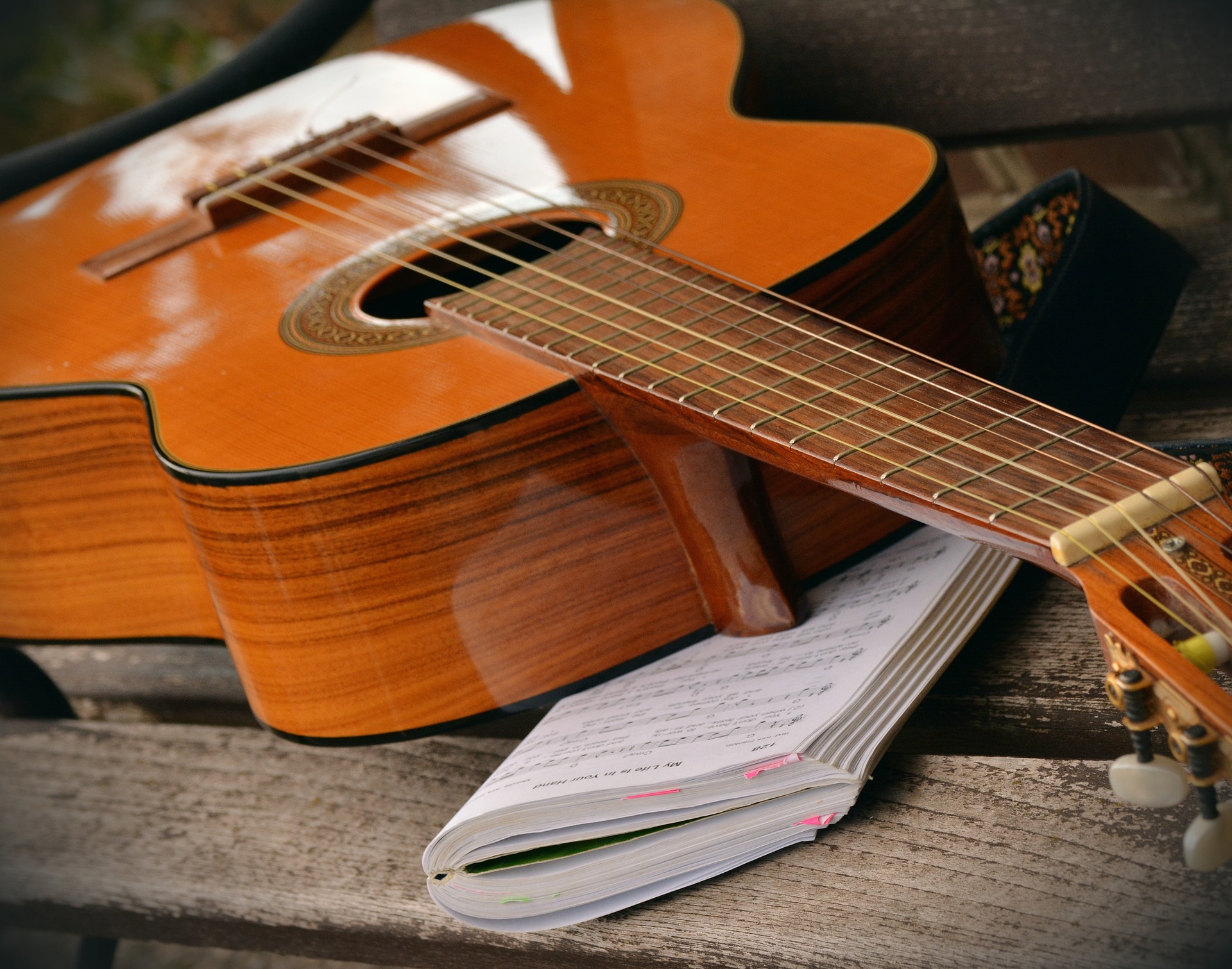 Gitarre und Liederheft auf einer Parkbank